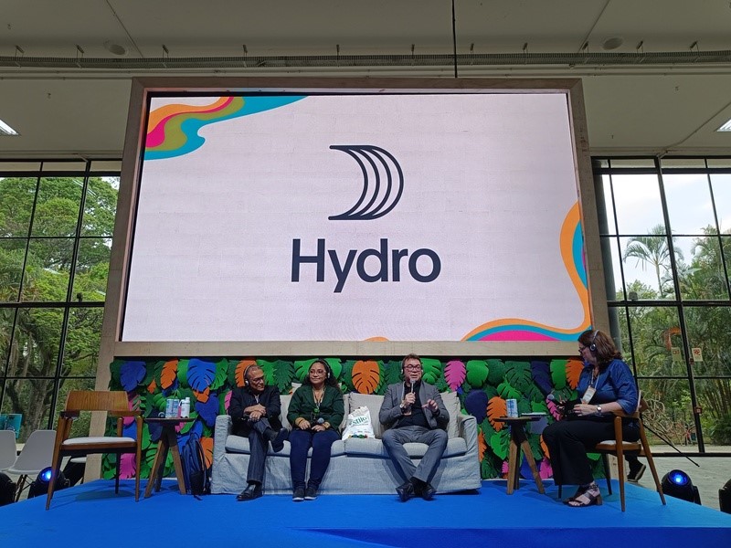 a group of people sitting on a stage in front of a large screen