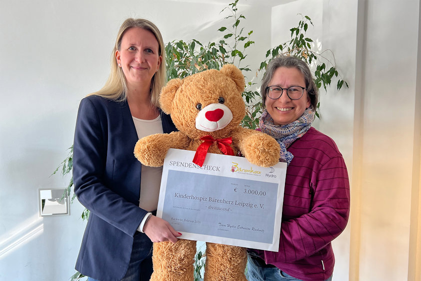 two women holding a large teddy bear