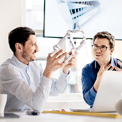 Two persons discussing an extruded object