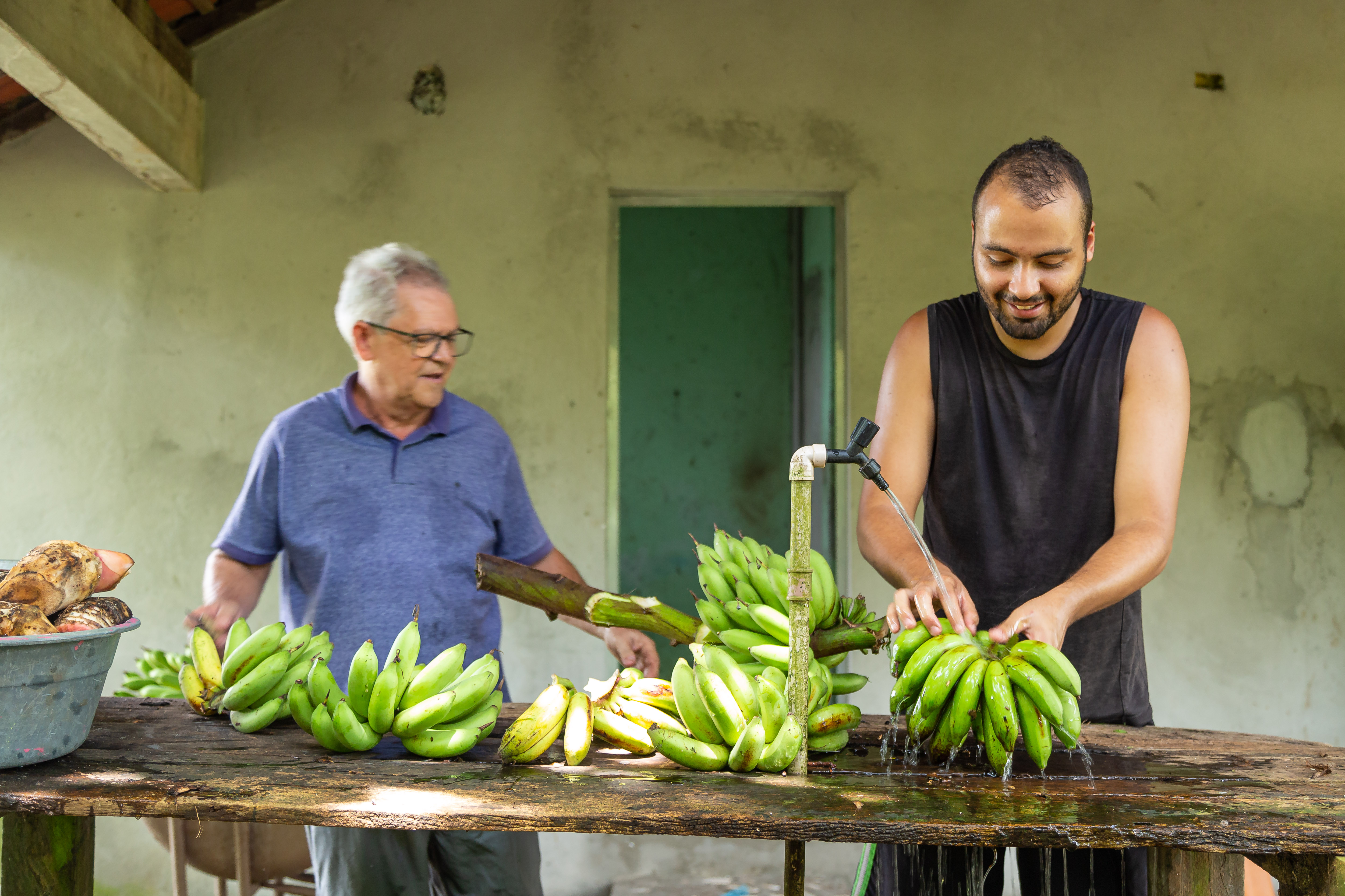 a couple of men stand near each other holding bananas